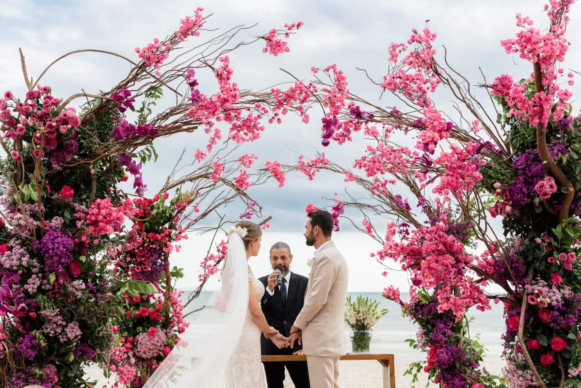 Casal trocando votos na praia ao pôr do sol
