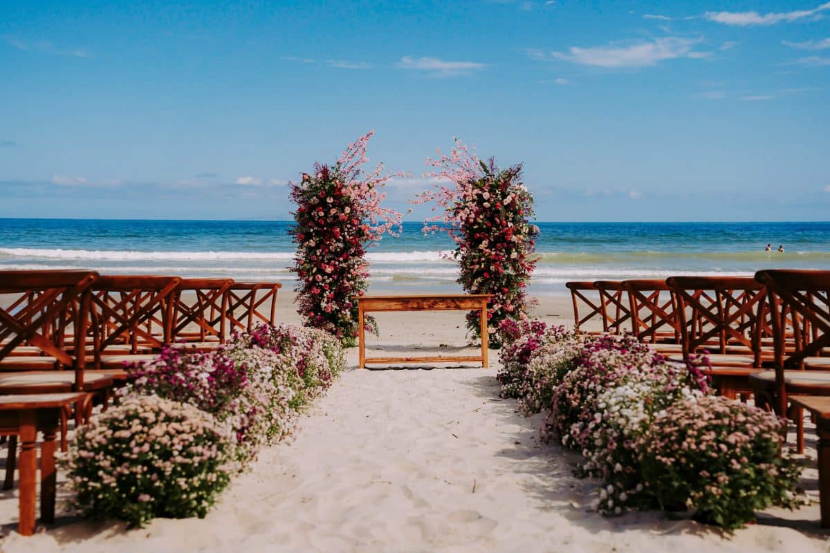 Casal trocando votos em casamento na praia de Juquey com o pôr do sol ao fundo